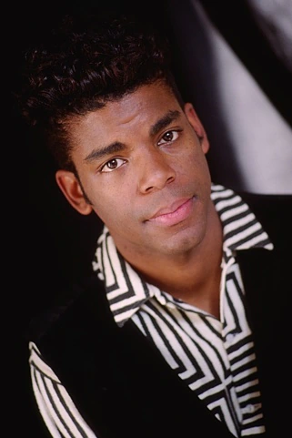 Original photo: A young man with curly hair wearing a black and white patterned jacket.